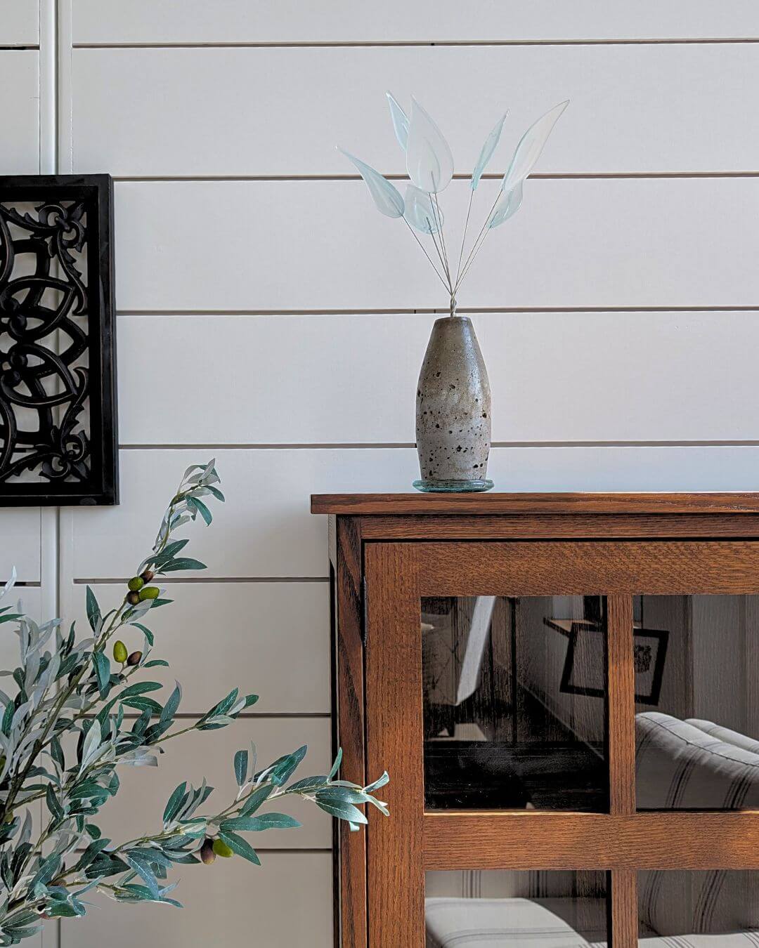 Low Maintenance Glass Plants in a decorative vase on a wooden table against a white wall.