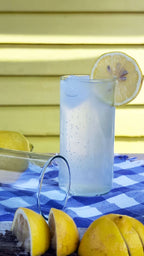 Upcycled drinking glasses filled with sparkling water and lemon slice on a blue checkered tablecloth.